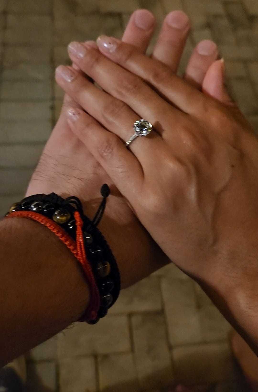 Angélica's hand showing her engagement ring resting on Esteban's hand
